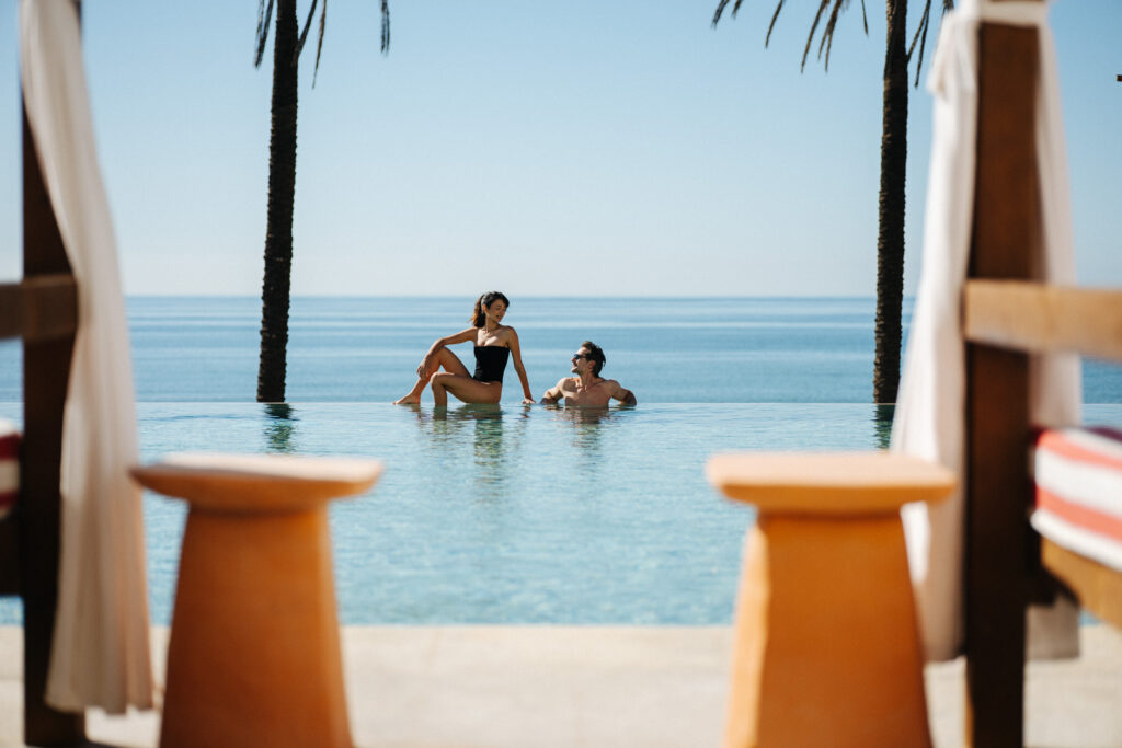 couple in a pool in a beach club by a hotel