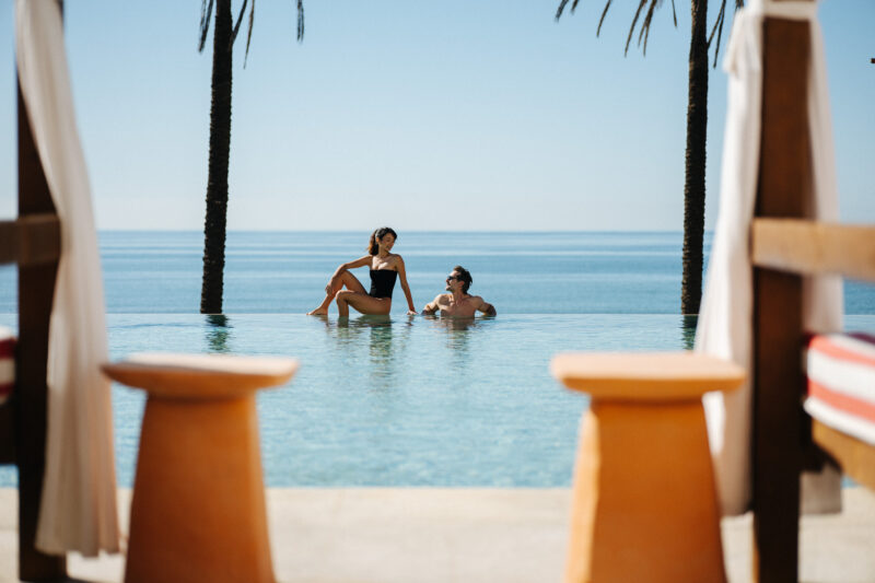couple in a pool in a beach club by a hotel