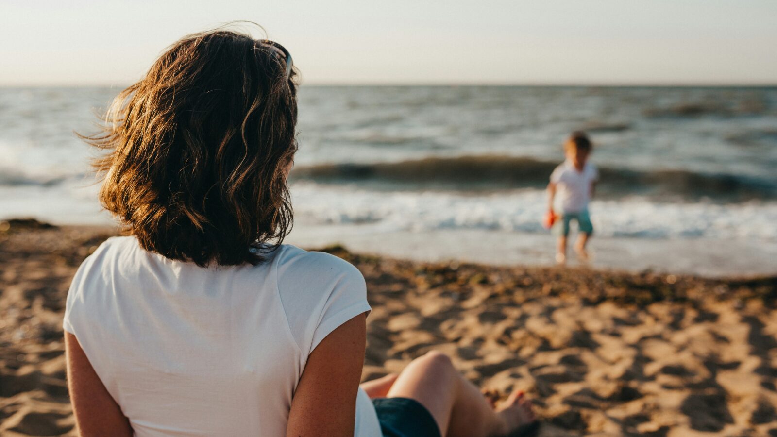 Woman on a beach facing a child