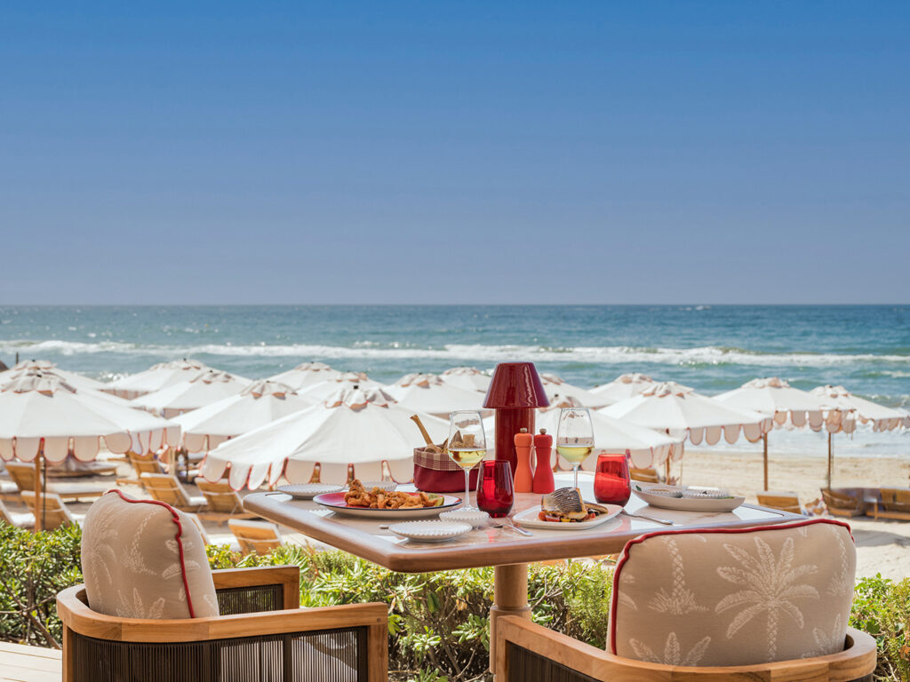 Mesa con platos y copas frente a la playa en Amù Beach Club.