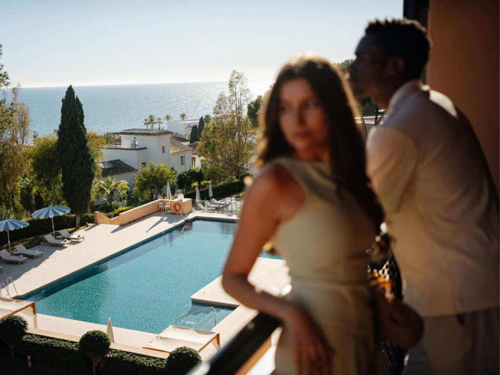 couple in room balcony with a pool and sea view